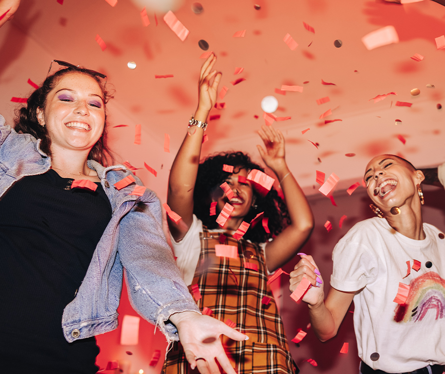 Tres mujeres celebrando entre confeti rojo por el mayor premio de La Primitiva.